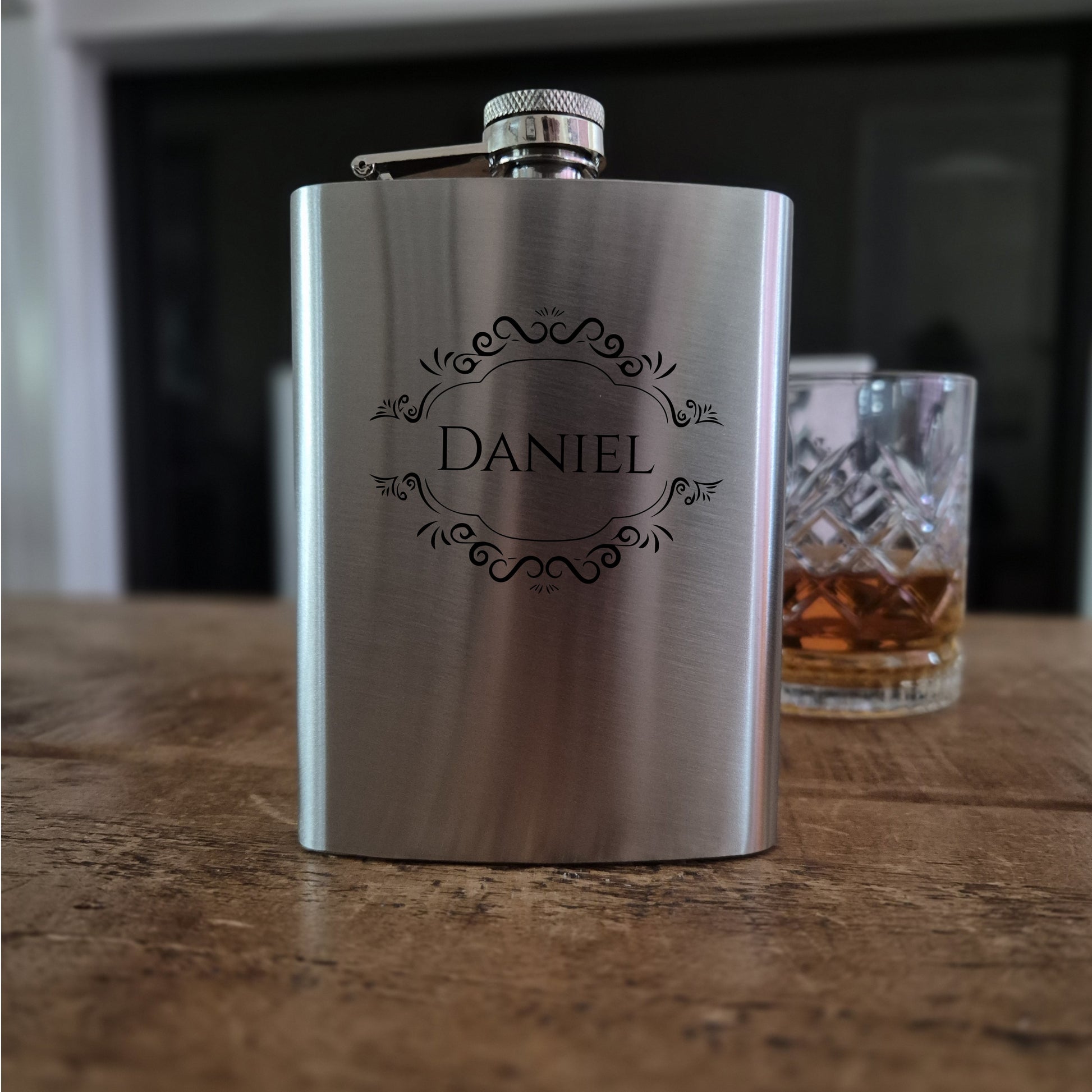 Stainless steel flask with 'Daniel' engraving on a wooden surface.