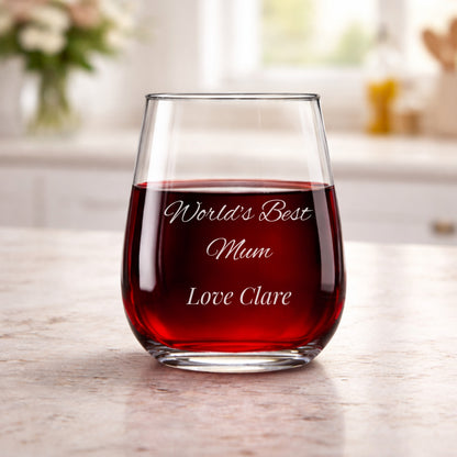 Glass of red wine with engraved message on a wooden surface