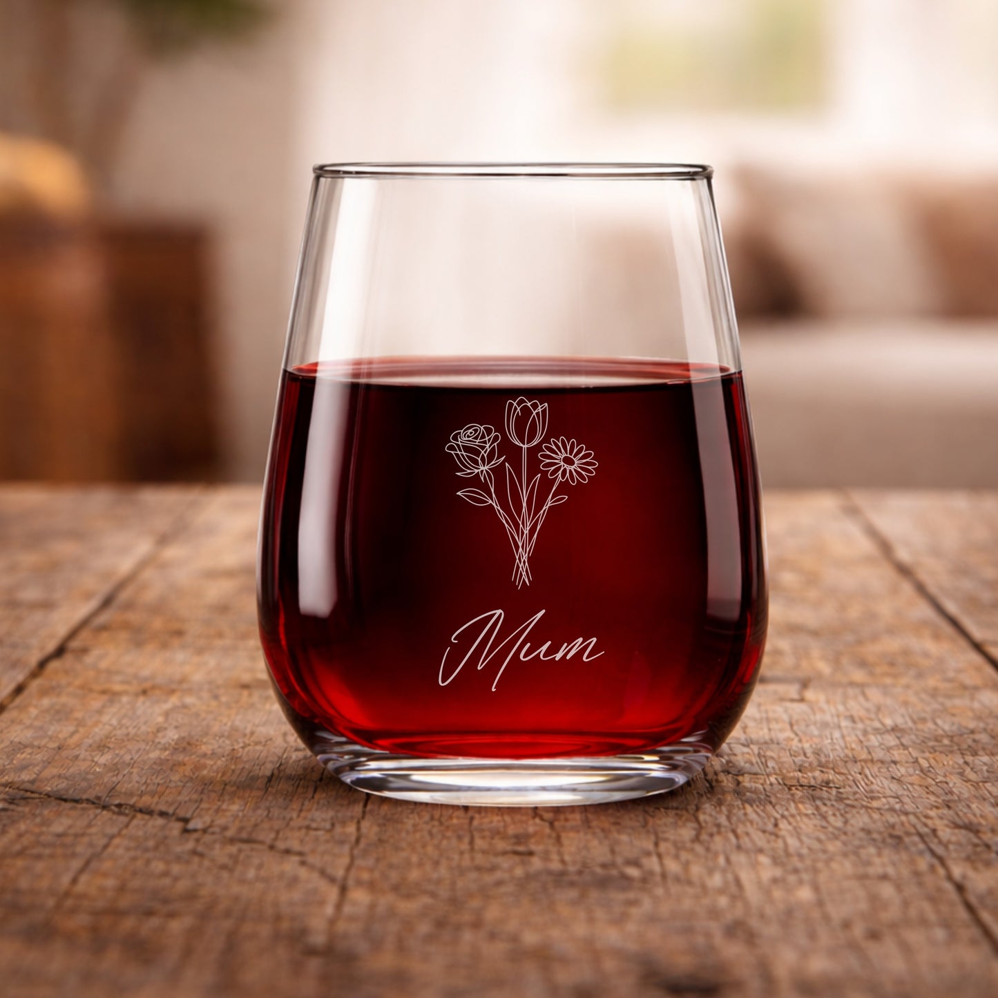 Glass of red wine with 'Mum' and floral design on a wooden table