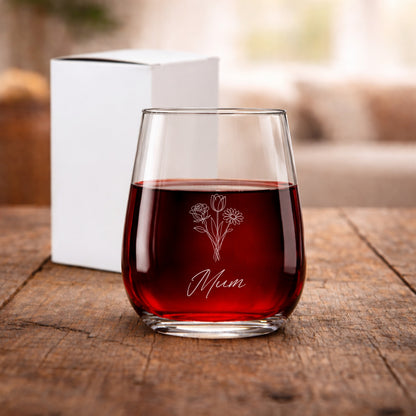 Glass of red wine with 'Mum' and floral design on a wooden surface