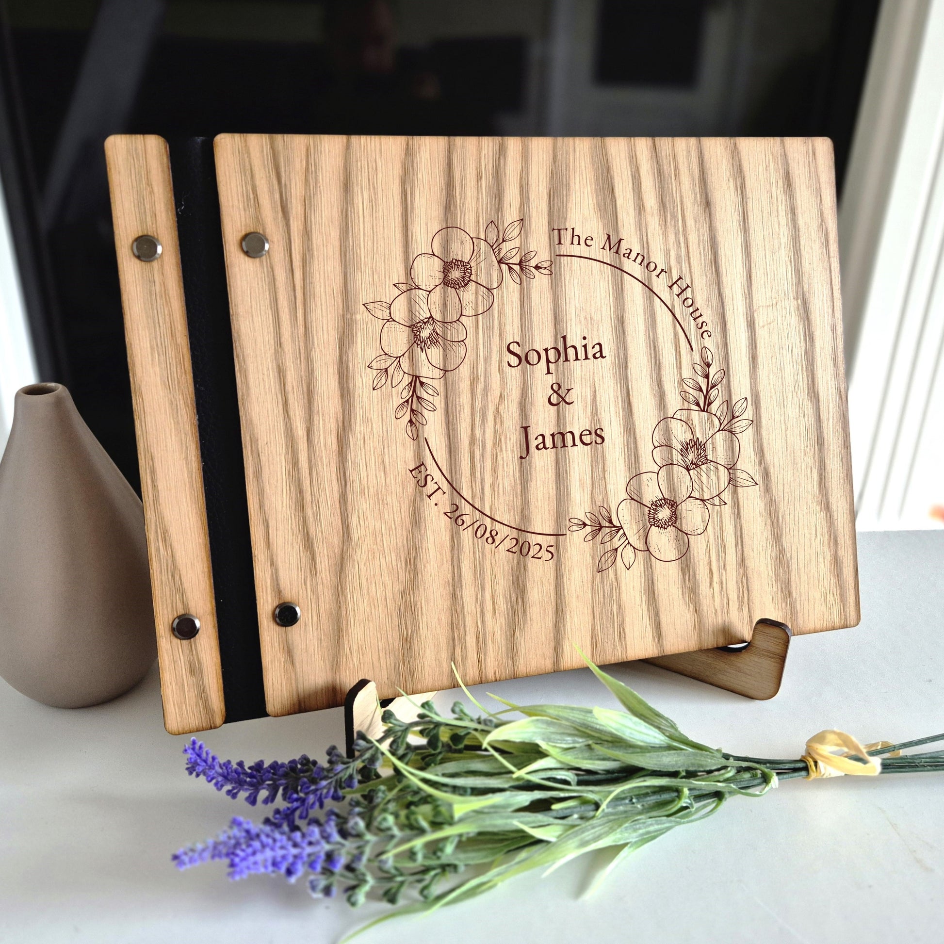 Image of a rustic style oak wedding book. The book is approximately 298mm x 216mm and includes high quality paper. The oak wedding book is laser engraved by laserengraveuk.com with a floral circular design to the front. The dsign includes the married couples names, date of wedding and the venue.