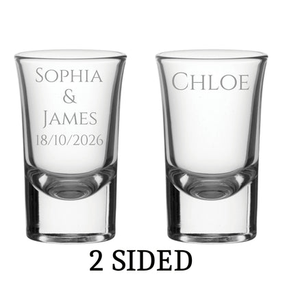 Two clear shot glasses with engraved names and date on a white background