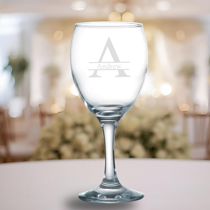 Clear wine glass with engraved 'Andrew' monogram on a blurred background