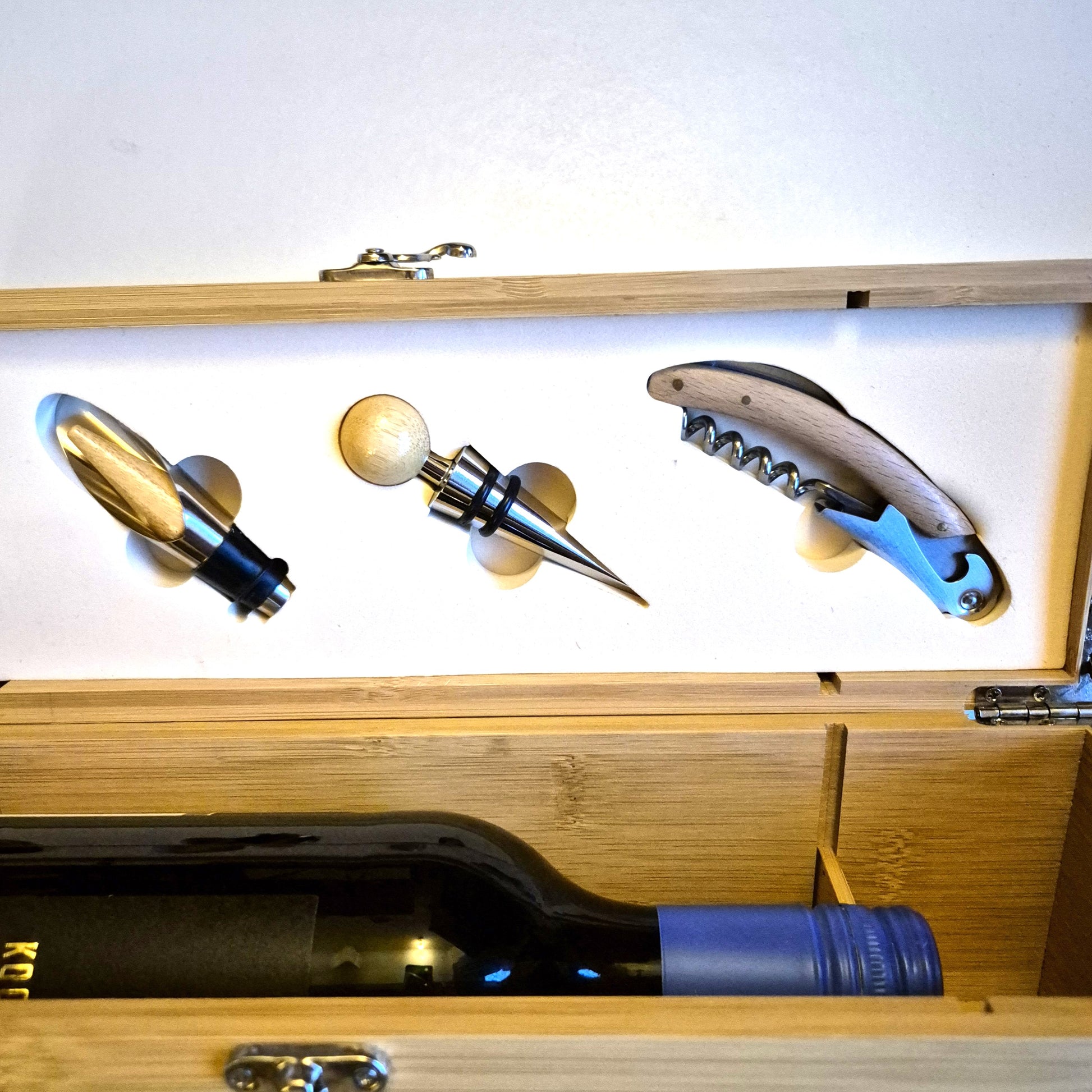 Wine bottle with corkscrew, bottle opener, and stopper in a wooden box.
