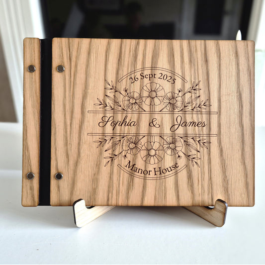 Image of a rustic style oak wedding book. The book is approximately 298mm x 216mm and includes high quality paper. The oak wedding book is laser engraved by laserengraveuk with a floral circular design to the front. The dsign includes the married couples names, date of wedding and the venue.