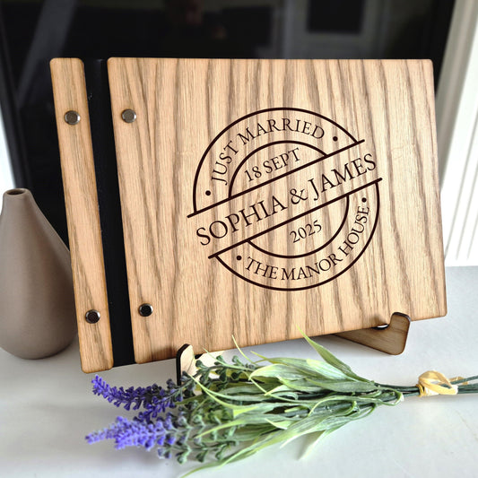 Image of a rustic style oak wedding book. The book is approximately 298mm x 216mm and includes high quality paper. The oak wedding book is laser engraved by laserengraveuk with a circular just married stamp design to the front. The design includes the married couple's names, date of wedding, and the venue.