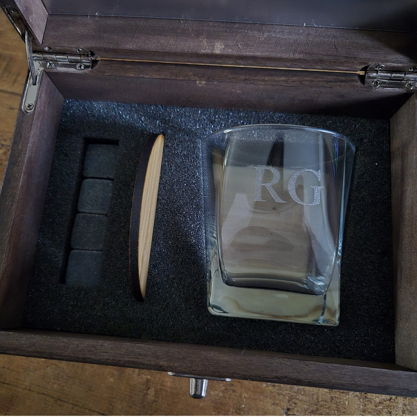 Wooden whisky box with engraved text containing an engraved whiskey glass, stones and oak coaster.