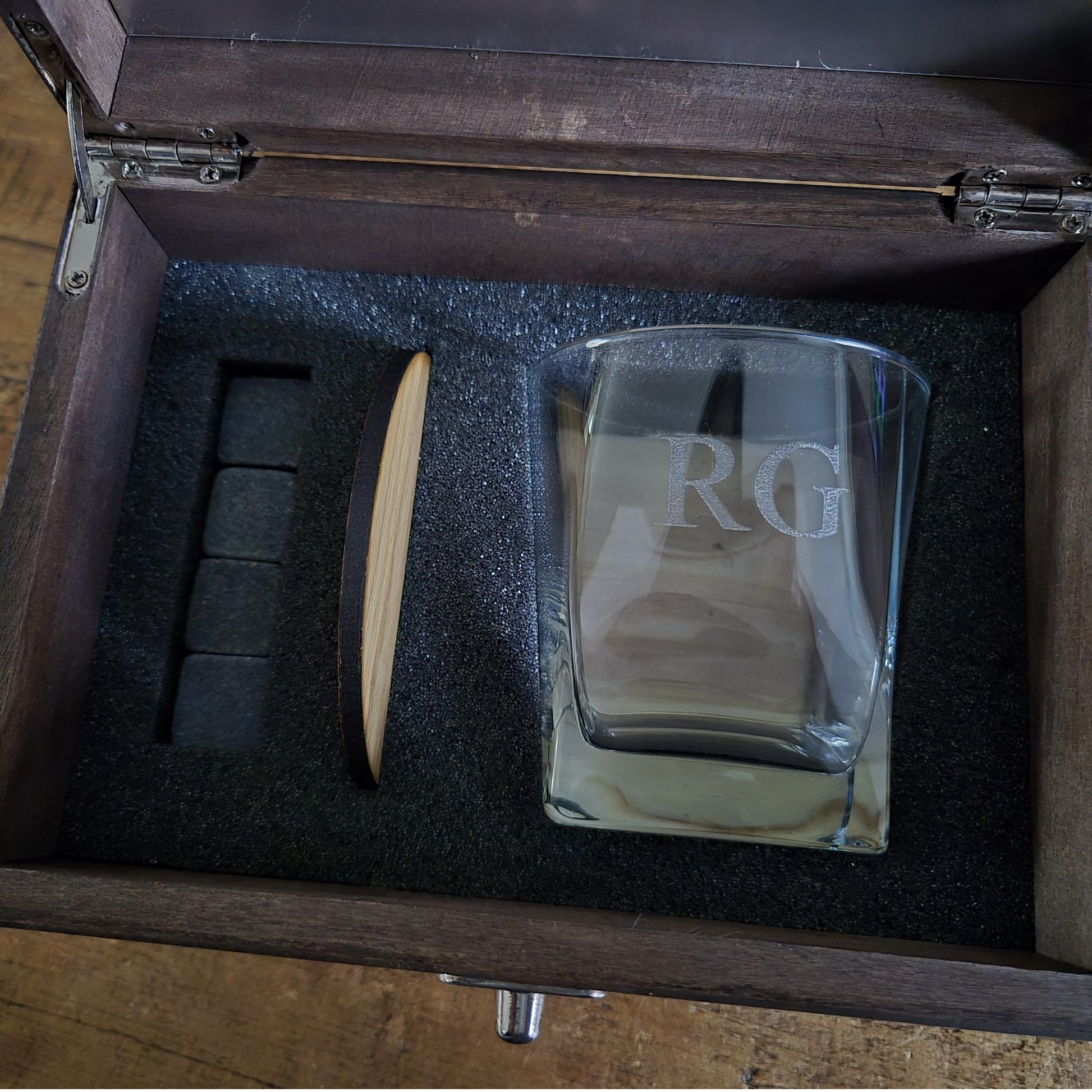 Wooden whisky box with engraved text containing an engraved whiskey glass, stones and oak coaster.