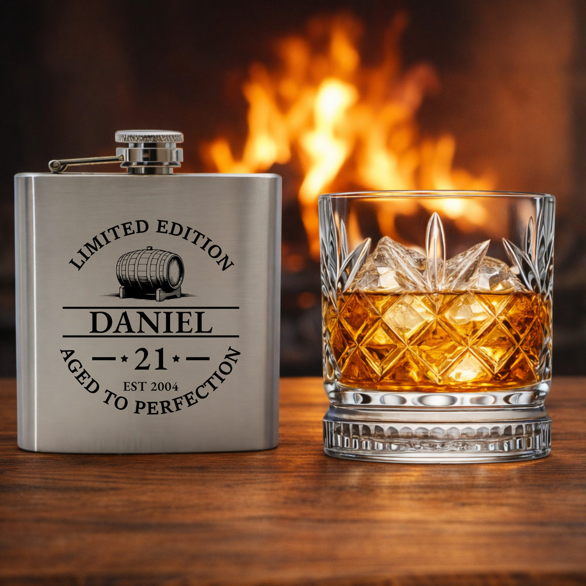 Personalized hip flask and glass with whiskey in front of a fireplace