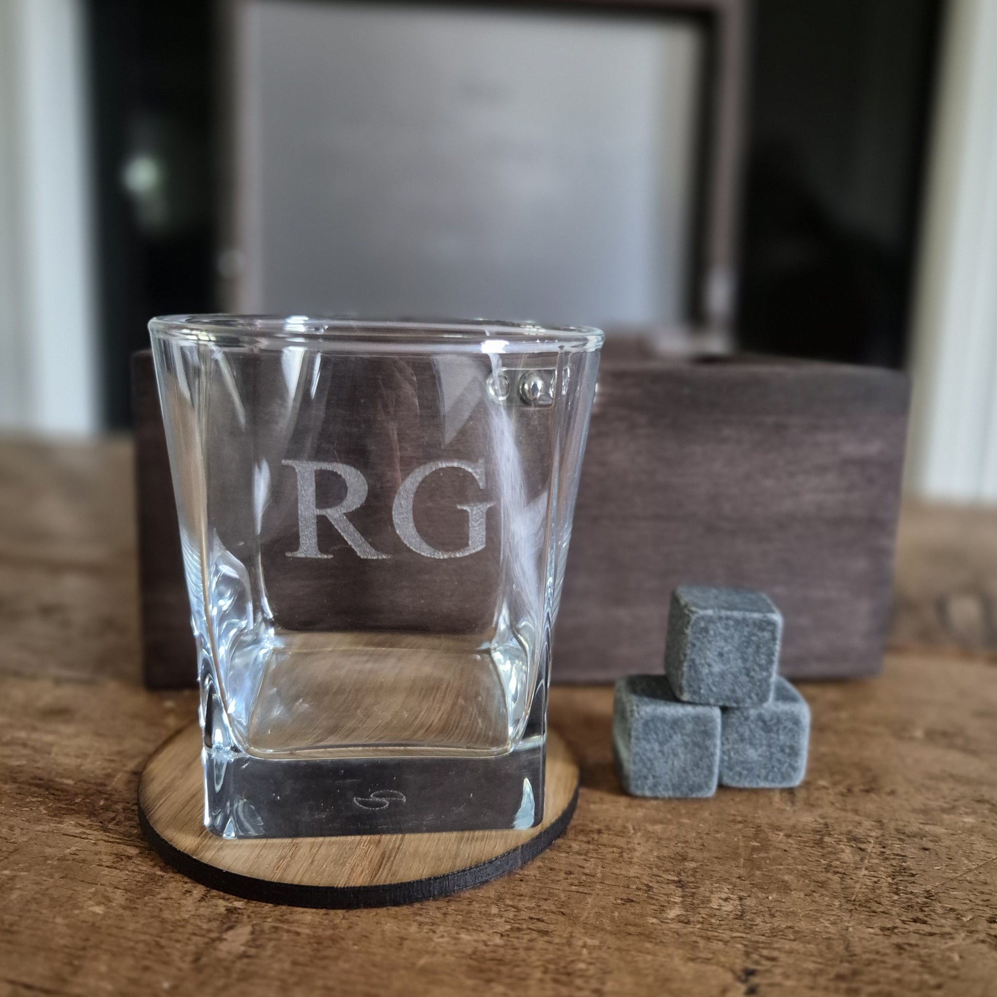 Wooden whisky box with engraved text containing an engraved whiskey glass, stones and oak coaster.